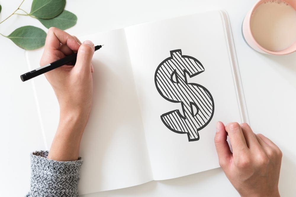 Close up of hands holding pen, drawing a dollar sign.