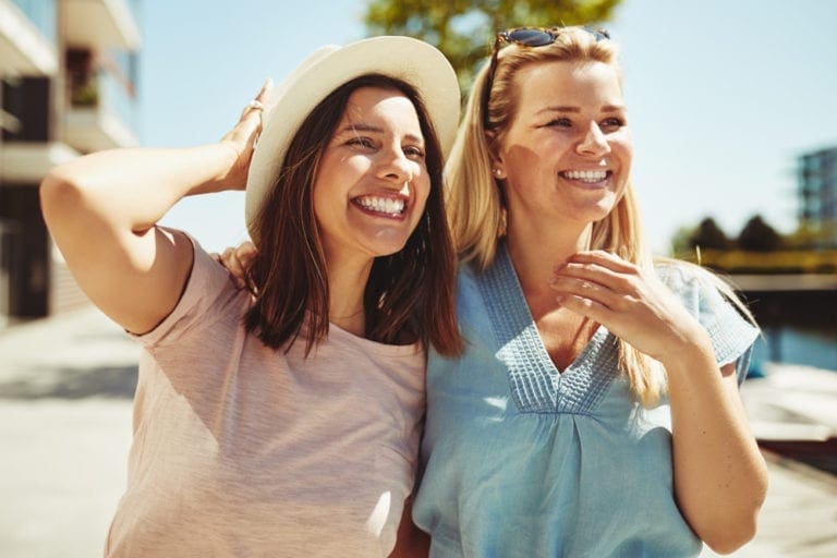 Two female friends enjoying a day outside together discussing breast augmentation.